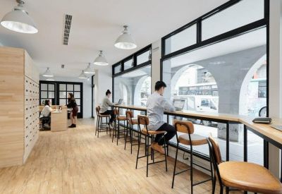 Bright communal workspace with a long wooden window bar and arched window frames.