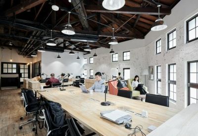 Spacious industrial-style coworking area with high timber ceilings and white brick walls.