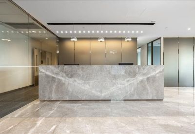 Professional reception area with a large grey marble desk and warm overhead lighting.