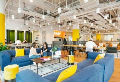 Spacious communal lounge with blue sofas, yellow accents, and industrial ceiling.