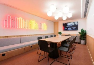 Meeting room with a long wooden table, neon wall art, and orb pendant lighting.