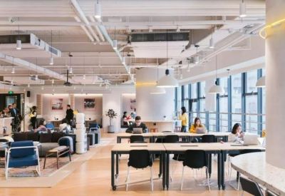 Spacious coworking area with long wooden tables and large windows letting in natural light.