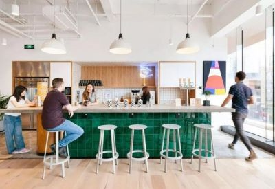 Vibrant communal kitchen area with a green tiled bar and modern pendant lighting.