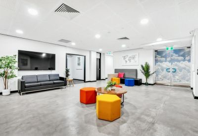 Vibrant communal lounge with colourful ottoman seating and a large wall-mounted screen.