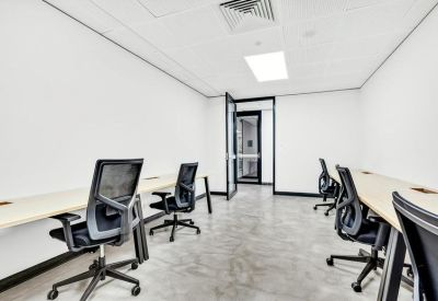 Spacious office suite with minimalist white desks and black mesh ergonomic chairs.