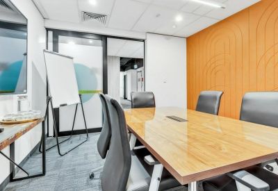 Modern meeting room with a wooden table, orange feature wall, and white board.