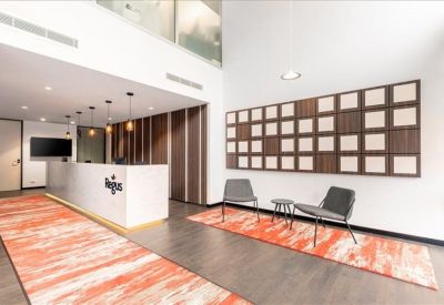 A modern reception desk with wood paneling and an orange patterned rug.