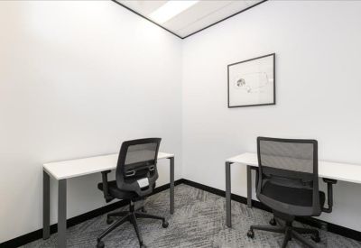 Private two-person office suite with white desks and black mesh chairs.
