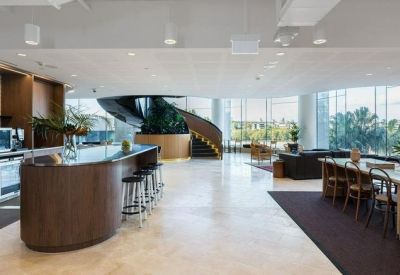 Spacious communal kitchen and lounge area featuring a curved dark wood island and spiral staircase.