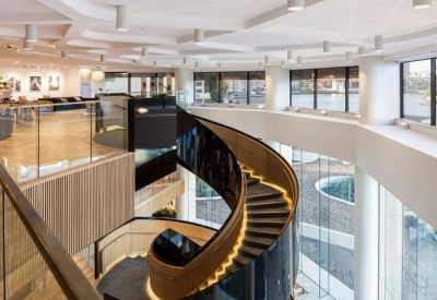 High-angle view of a dramatic dark spiral staircase with illuminated steps and glass railings.