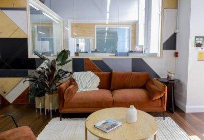 Lounge area at 123 Margaret Street featuring a velvet sofa, round coffee table, and patterned feature wall.