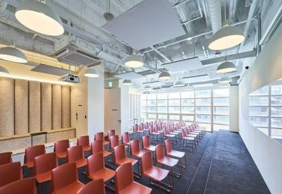 Large meeting room with rows of red chairs and multiple modern pendant lights.