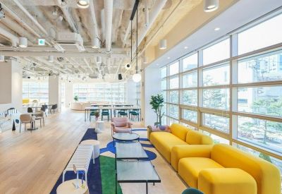 Bright coworking area with yellow modular seating and floor-to-ceiling windows.