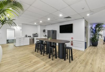 Breakout area featuring a high timber table with black stools and a wall-mounted TV.