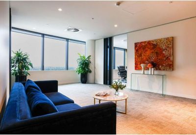 Bright lounge area with a blue velvet sofa and vibrant orange artwork.