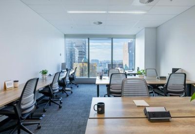 Bright open-plan workspace with multiple desks and large windows.