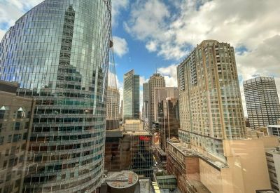 Wide view of high-rise city skyscrapers under a blue sky.