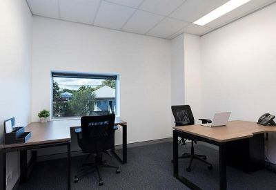 Internal two-person office suite with wooden desks and ergonomic black chairs.