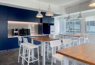 Communal break area with a kitchen, dark blue cabinetry, and high-top wooden tables.