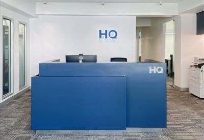 Bright reception desk in navy blue with prominent HQ branding on a white wall.