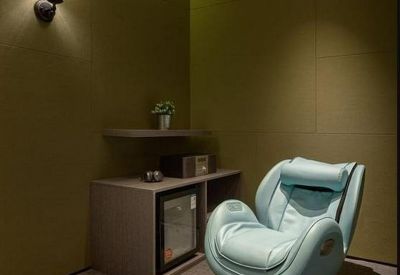 Private relaxation room featuring a light blue massage chair and warm wall lighting.