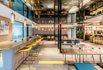 Modern open-plan café area with bar seating and vibrant yellow stools.