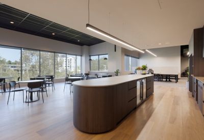 Communal kitchen and breakout area with a large island bench and dining tables.