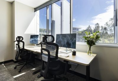 Bright private office with dual monitors, ergonomic chairs, and large window views.