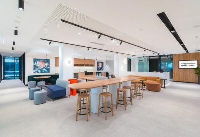 Spacious communal area with long wooden bar table and colourful seating pods.