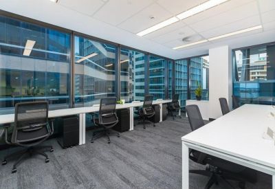 Bright corner workspace with several desks and high-rise city views.