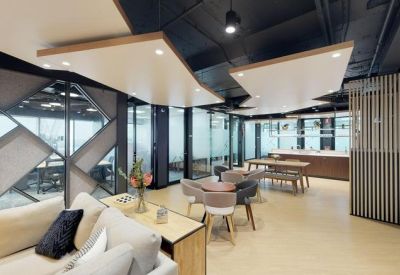 Spacious communal breakout area with a sofa, café seating, and geometric wall panels.