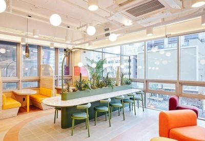 Coworking space featuring a long central planter table and colorful booth seating.