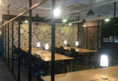 Industrial style workspace with long wooden desks and individual desk lamps.