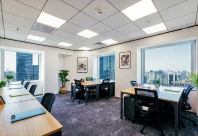 Bright shared office space with wooden desks, ergonomic chairs, and large windows.