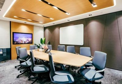 Large professional boardroom with a long light-wood table and grey ergonomic chairs.