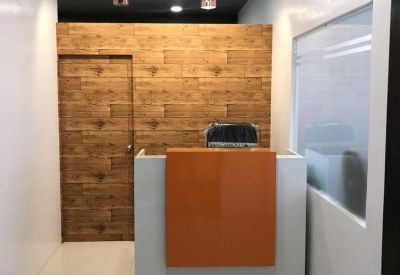 Minimalist reception area with an orange and white desk set against a wood-paneled feature wall.