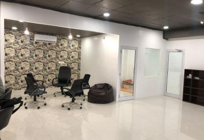Open-plan meeting area with patterned wallpaper, black office chairs, and a bean bag.
