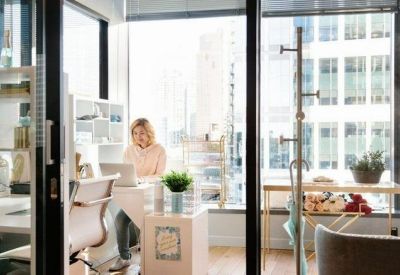 Modern private office with a desk facing a large window and views of the city buildings.