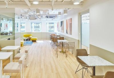 Sunny cafe-style breakout area with small marble tables and warm lighting.