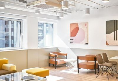 Modern lounge area featuring leather armchairs, yellow ottomans, and abstract wall art.
