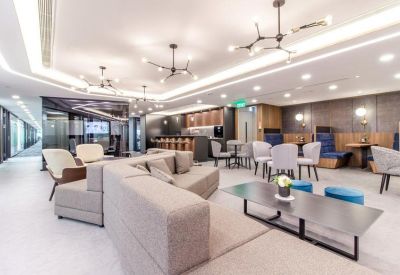 Modern communal lounge with a large L-shaped sofa, coffee table, and cafe-style seating.
