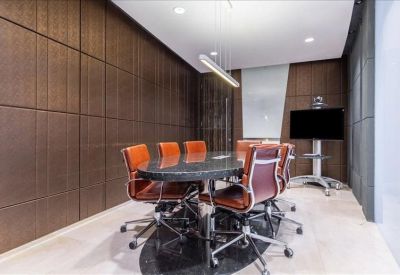Boardroom with dark wood paneled walls and brown leather seating.