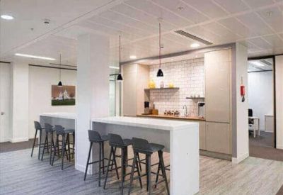 Contemporary office kitchen and breakout area with white breakfast bar and pendant lighting.