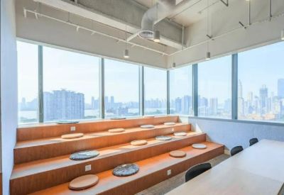 Bright breakout space featuring tiered wooden bleacher seating and floor-to-ceiling city views.