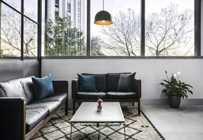 Leather sofas in a bright lounge area overlooking city trees.