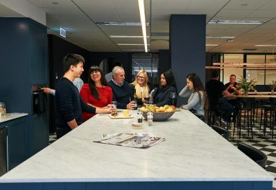 People gathered around a large marble kitchen island in a modern breakout area.