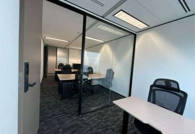 Bright glass-partitioned private office with two workstations and ergonomic black chairs.