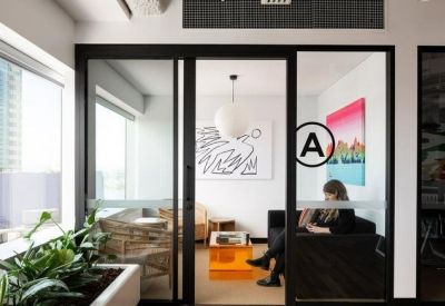 Glass-walled private office suite featuring colorful wall art and an orange coffee table.