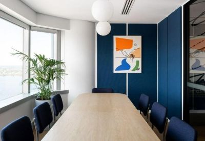 Professional meeting room with a long wooden table, blue chairs, and blue acoustic wall panels.