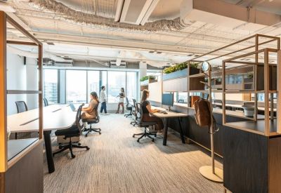 Spacious open-plan workspace with modern desks and floor-to-ceiling windows.